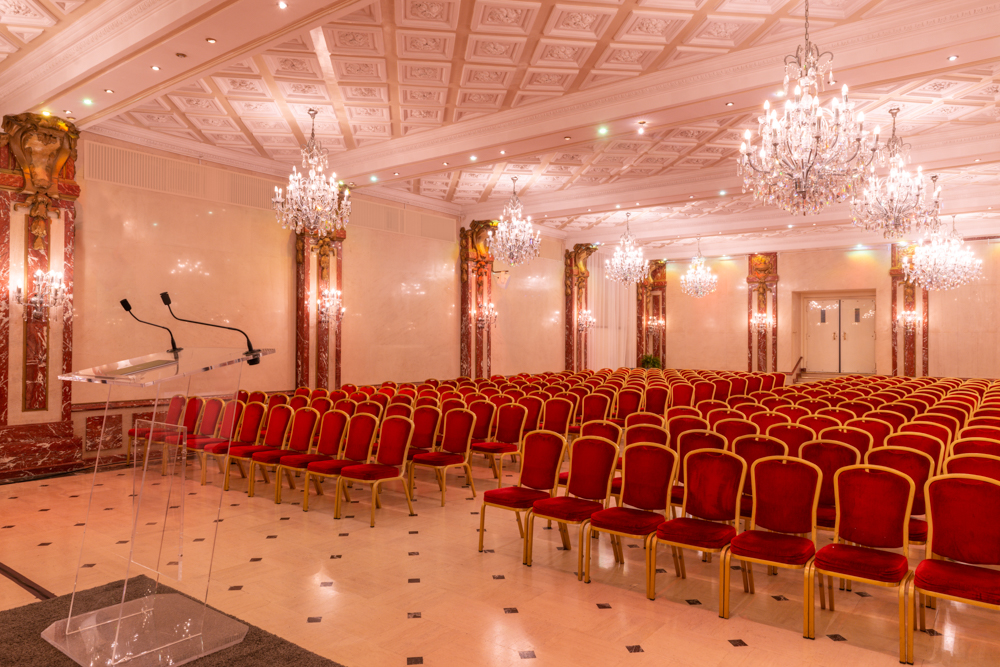 Elegant 100th Euroconstruct conference room with rows of red velvet chairs and crystal chandeliers