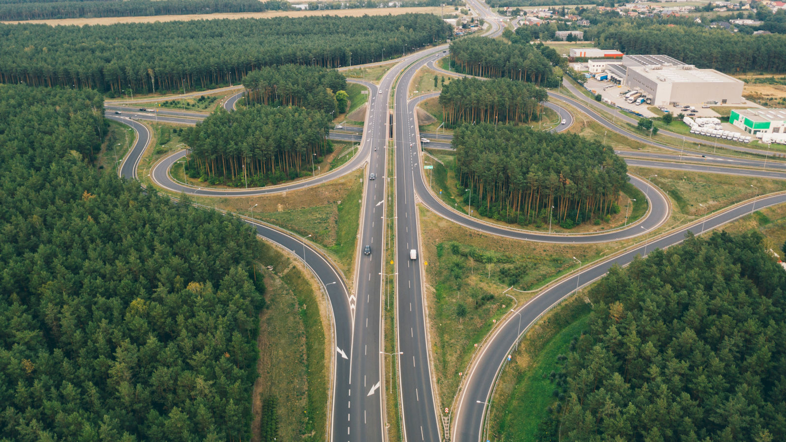 Aerial view of a highway interchange surrounded by dense forest.